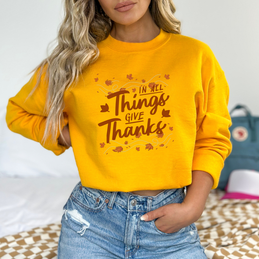 The hand-lettered phrase: "In All Things Give Thanks" in a warm, earthy brown/orange tone.
Autumnal elements: Maple leaves swirling around the text as if being carried by a light breeze.
The overall style is hand-drawn script/lettering with a focus on a clear, positive message.
Overall Theme: Gratitude, Thanksgiving, Autumn, and Positive/Inspirational Message.