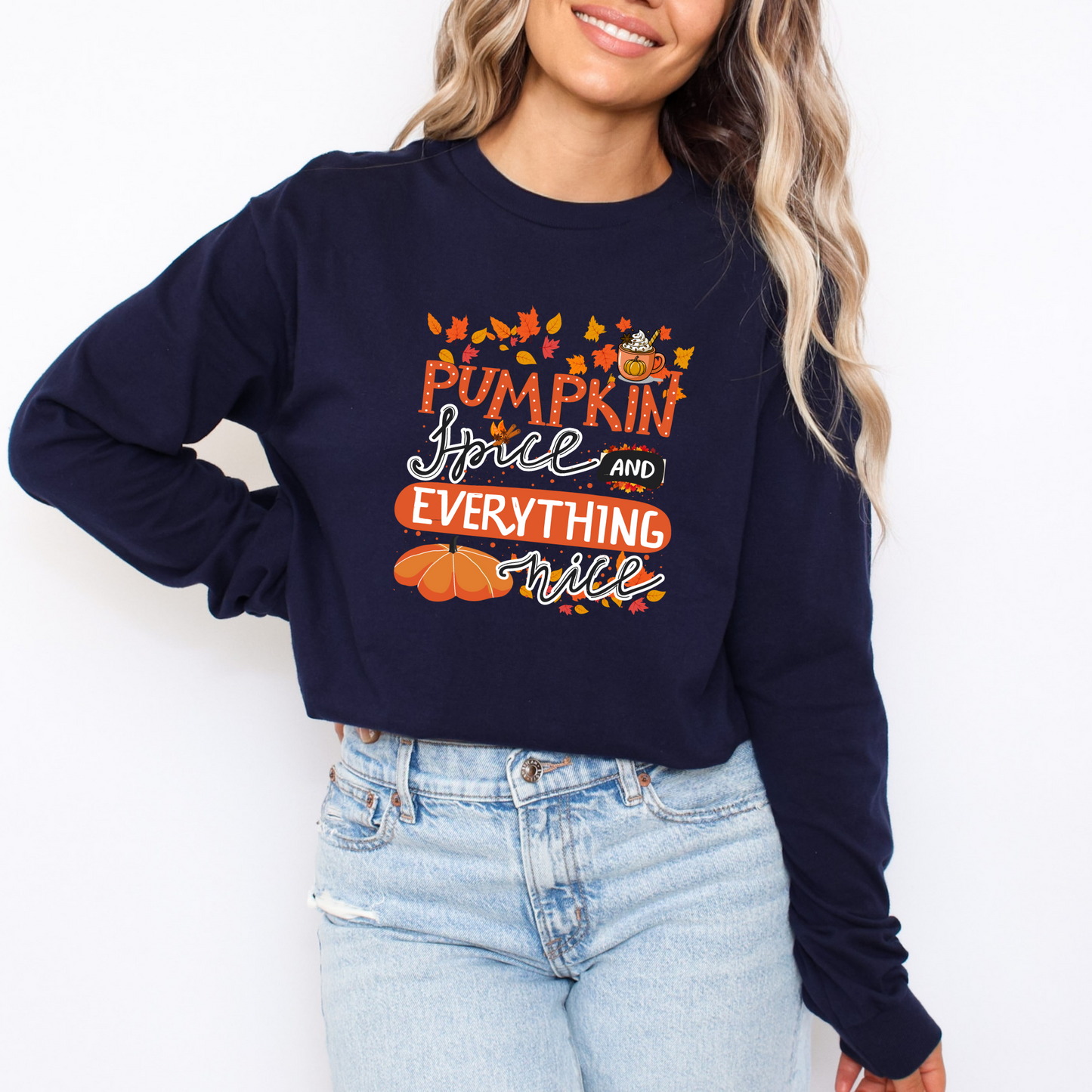 Person wearing a navy sweatshirt with 'Pumpkin Spice and Everything Nice' text and pumpkins design featuring a colorful graphic design with the text "PUMPKIN" in large orange dotted letters at the top. Below it, "Spice" is written in a black flowing cursive, accented with cinnamon sticks and star anise. To the right, "AND" is in a black banner shape. Underneath, "EVERYTHING" is in stacked orange sans-serif capital letters, and "nice" is written in a black flowing cursive at the bottom. The design is decora