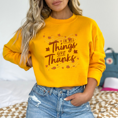 The hand-lettered phrase: "In All Things Give Thanks" in a warm, earthy brown/orange tone.

Autumnal elements: Maple leaves swirling around the text as if being carried by a light breeze.

The overall style is hand-drawn script/lettering with a focus on a clear, positive message.

Overall Theme: Gratitude, Thanksgiving, Autumn, and Positive/Inspirational Message.