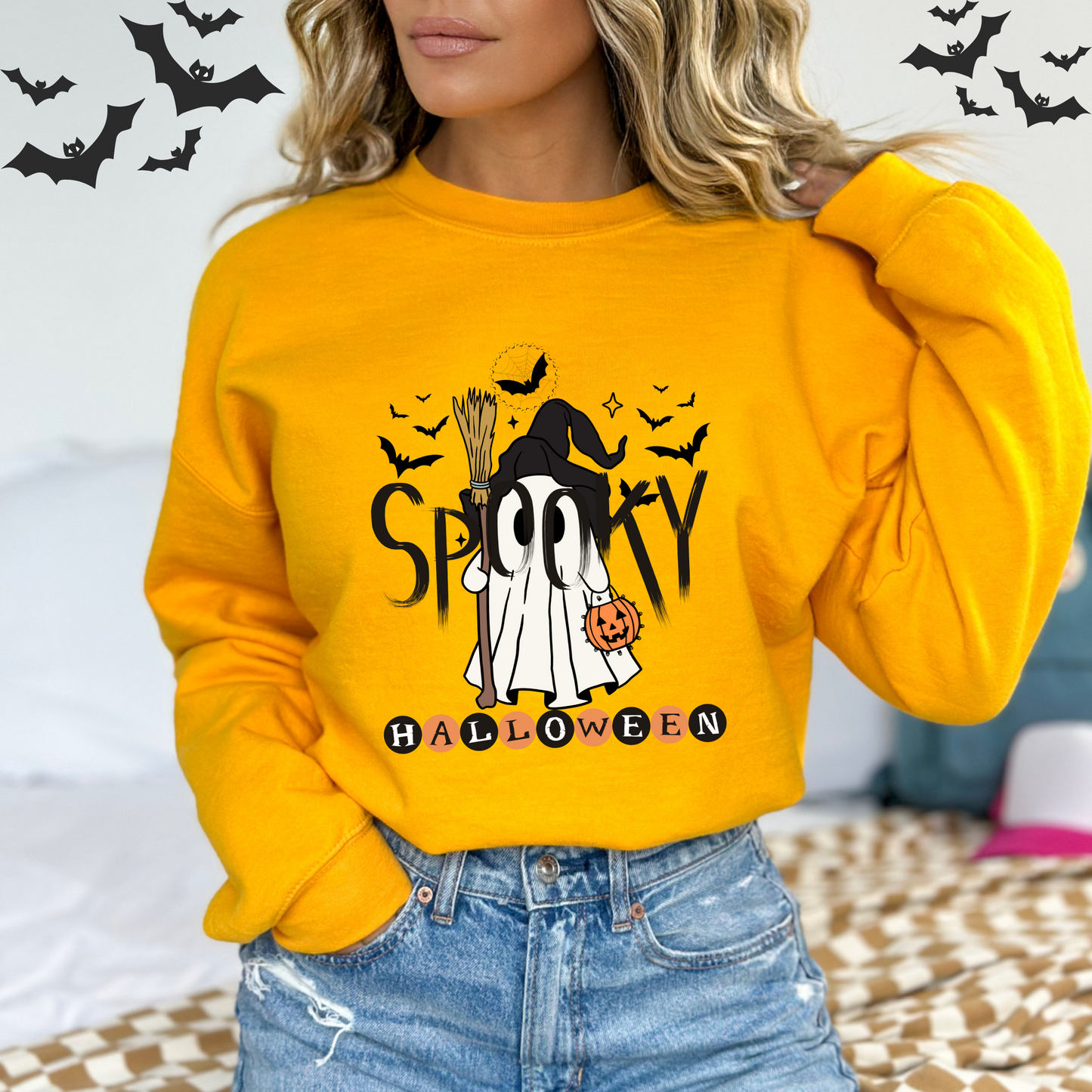 Person wearing a yellow Halloween-themed sweatshirt with a ghost and text design.