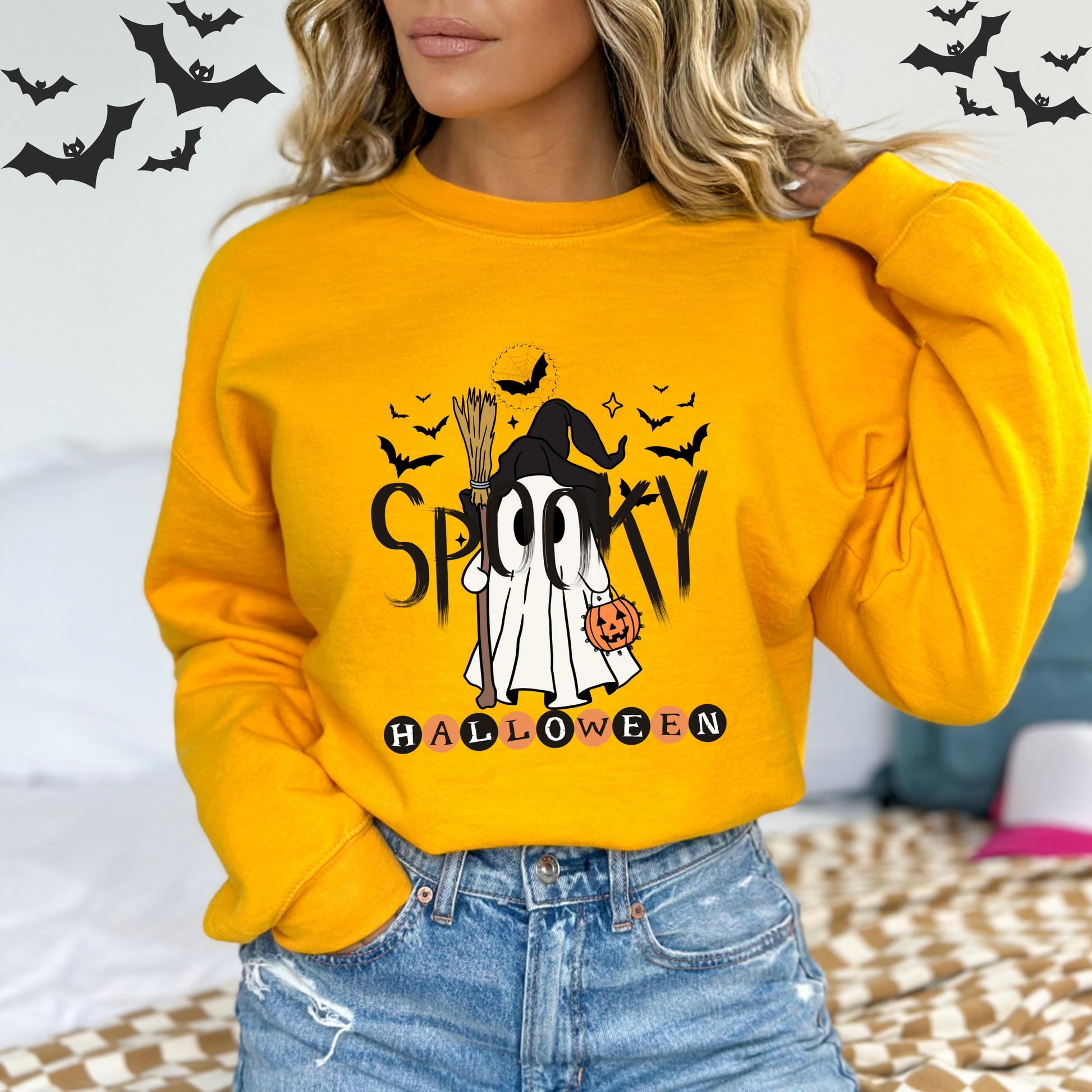 Person wearing a yellow Halloween-themed sweatshirt with a ghost and text design.