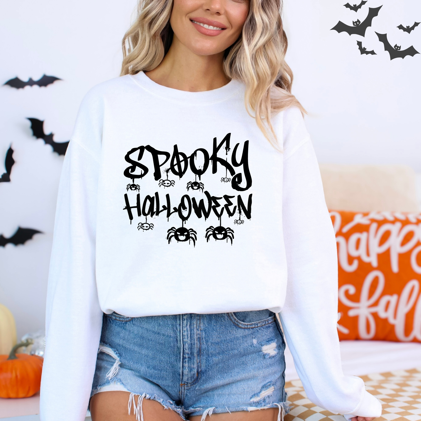 Person wearing a white sweatshirt with 'Spooky Halloween' text, surrounded by Halloween decorations.