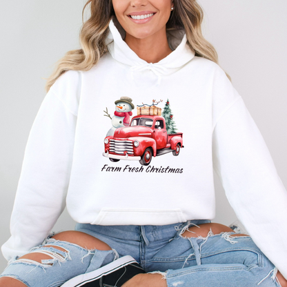 Woman wearing a white hoodie with a red truck and snowman design, sitting against a plain background.