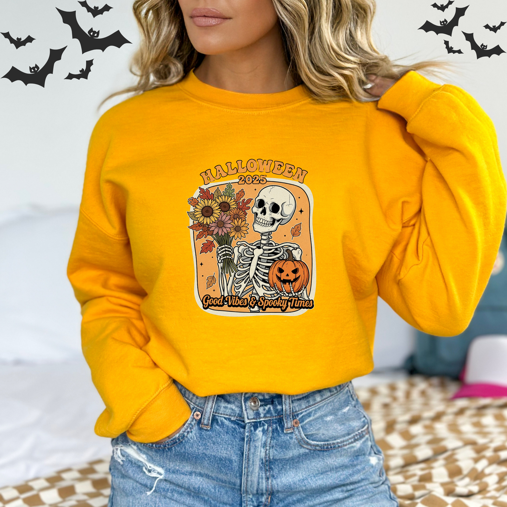 Person wearing a yellow Halloween sweatshirt with a skeleton and pumpkin design.