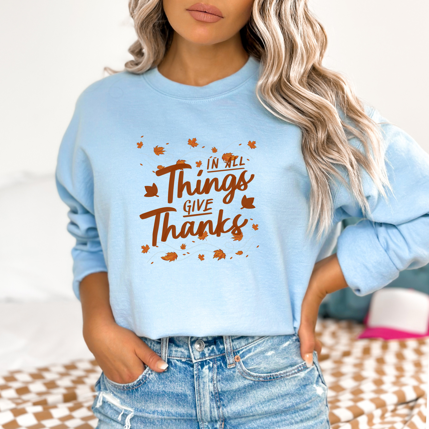 Light blue sweatshirt with 'In all things give thanks' text worn by a person.