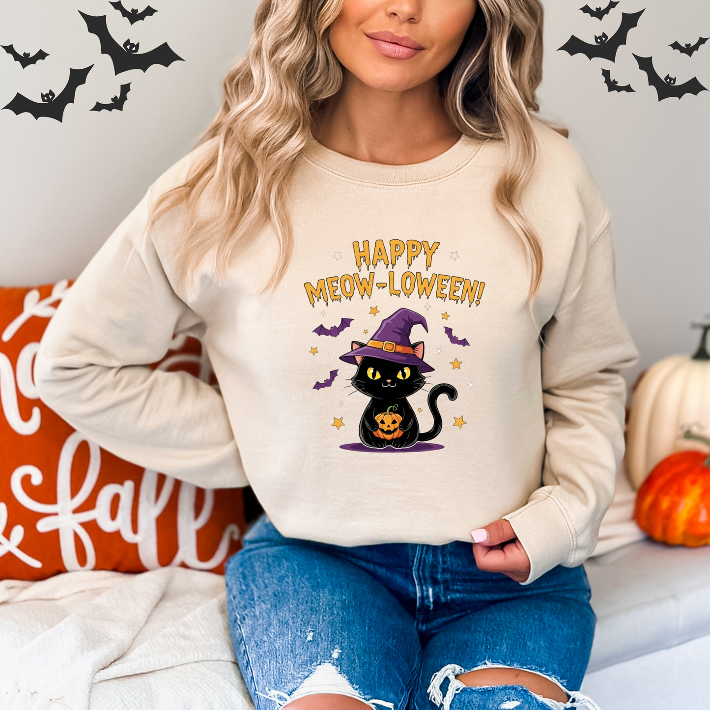 Person wearing a Halloween-themed sweatshirt with a black cat and text, sitting on a couch An illustration of a cute black cat wearing a purple witch hat and holding a carved pumpkin. Bats and stars are in the background.