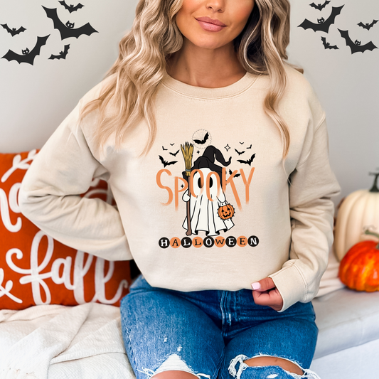 Person wearing a Halloween-themed sweatshirt with Witch Ghost with pumpkins and bats in the background.
